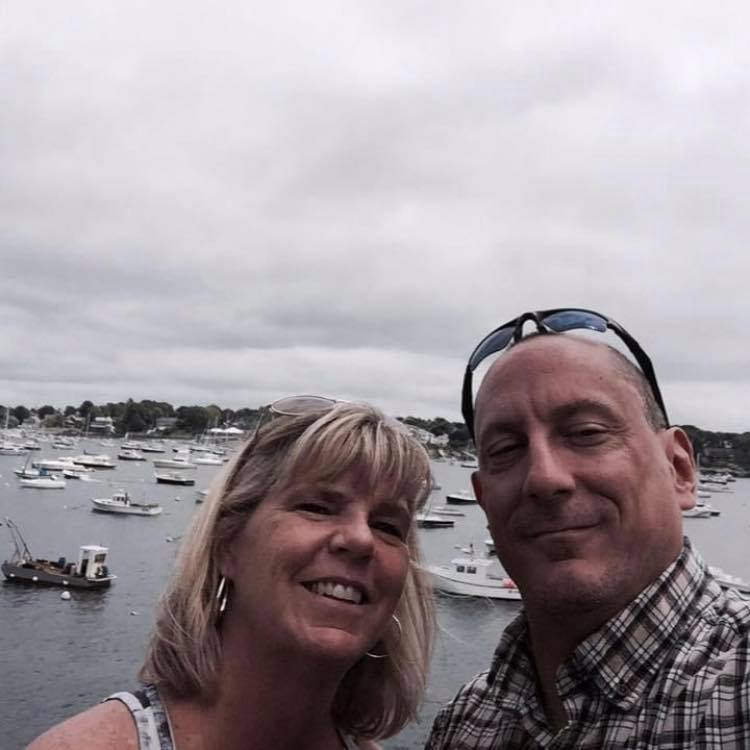 A man and woman taking a selfie in front of a harbor.
