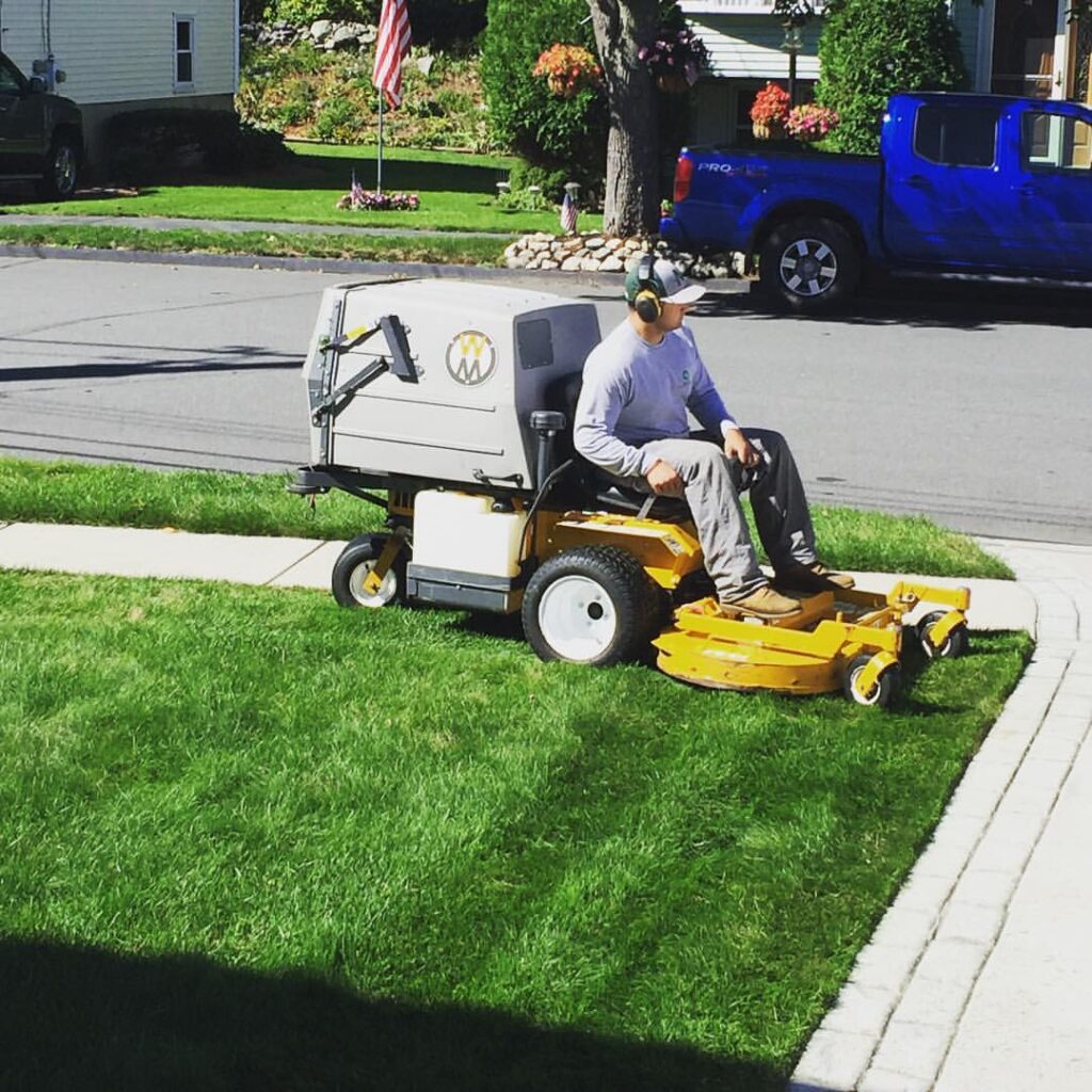 A man on a lawn mower in front of a house.