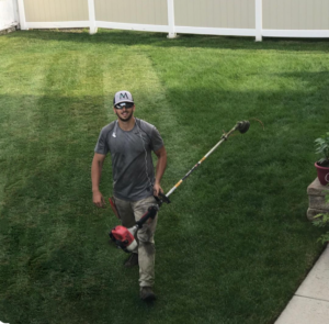 A man with a lawn mower in a backyard.