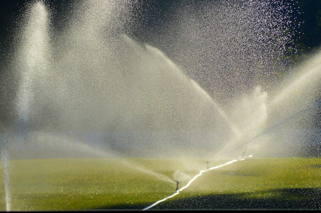 A sprinkler is spraying water on a grassy field.