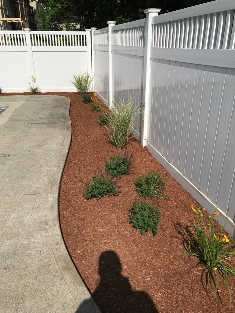 A backyard with a white fence and plants.