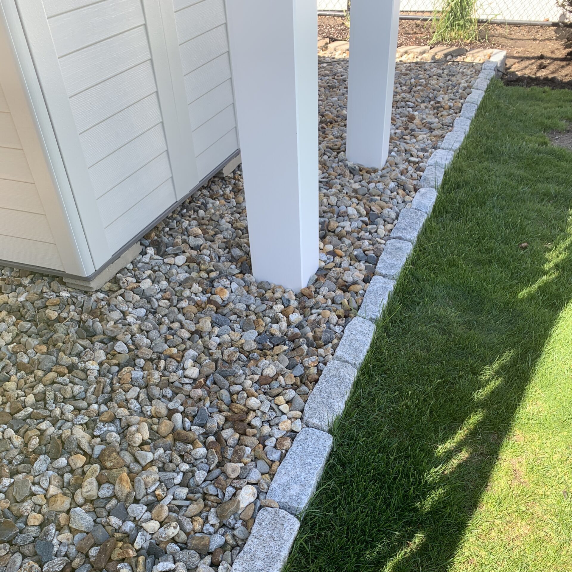 A yard with a gravel path and a white fence.