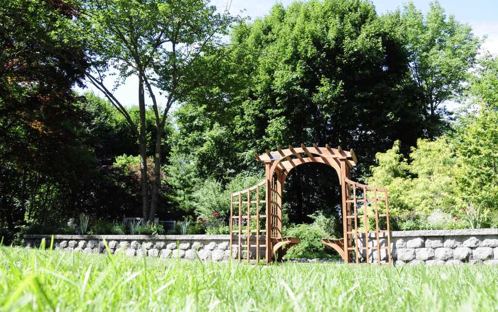 A wooden arch in a grassy area.