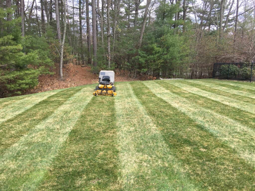 A lawn mower is mowing a lawn in a yard.