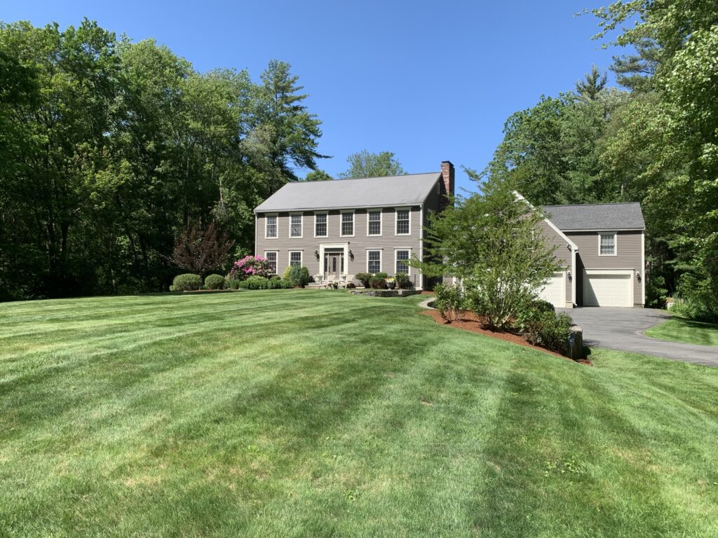 A large home with a large lawn and trees.