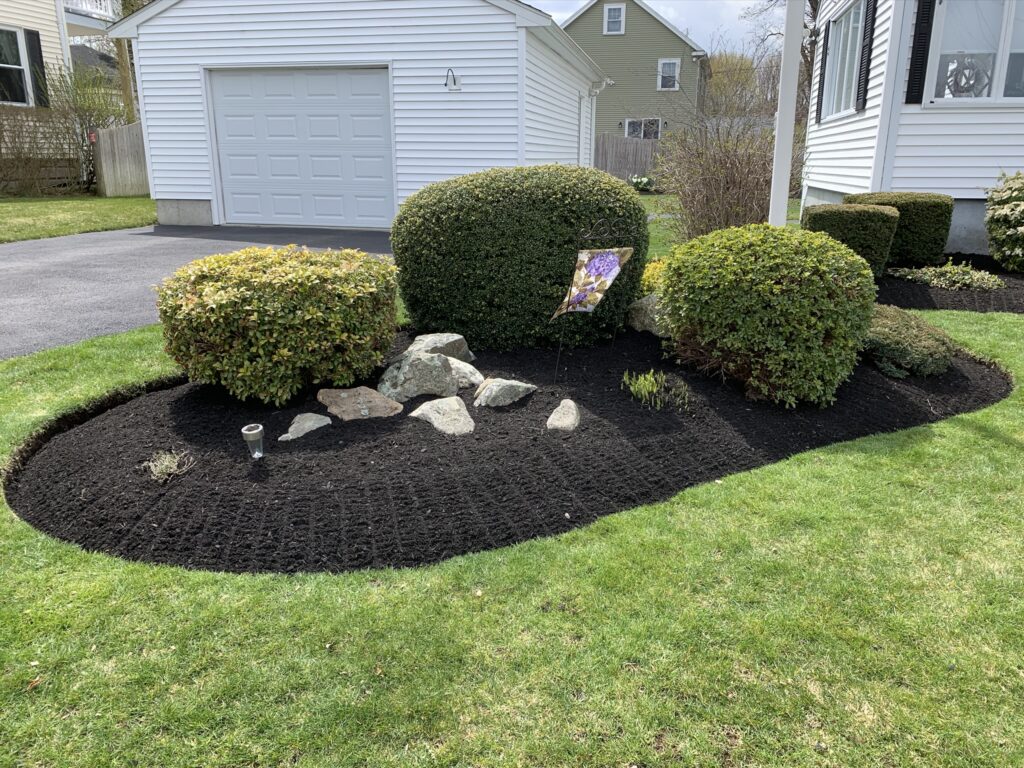 A black mulched flower bed in front of a house.