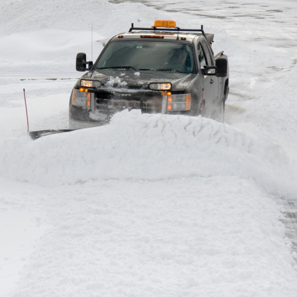 A truck plows a snowy road.