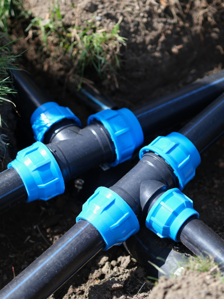 A group of blue and black pipes in the ground.